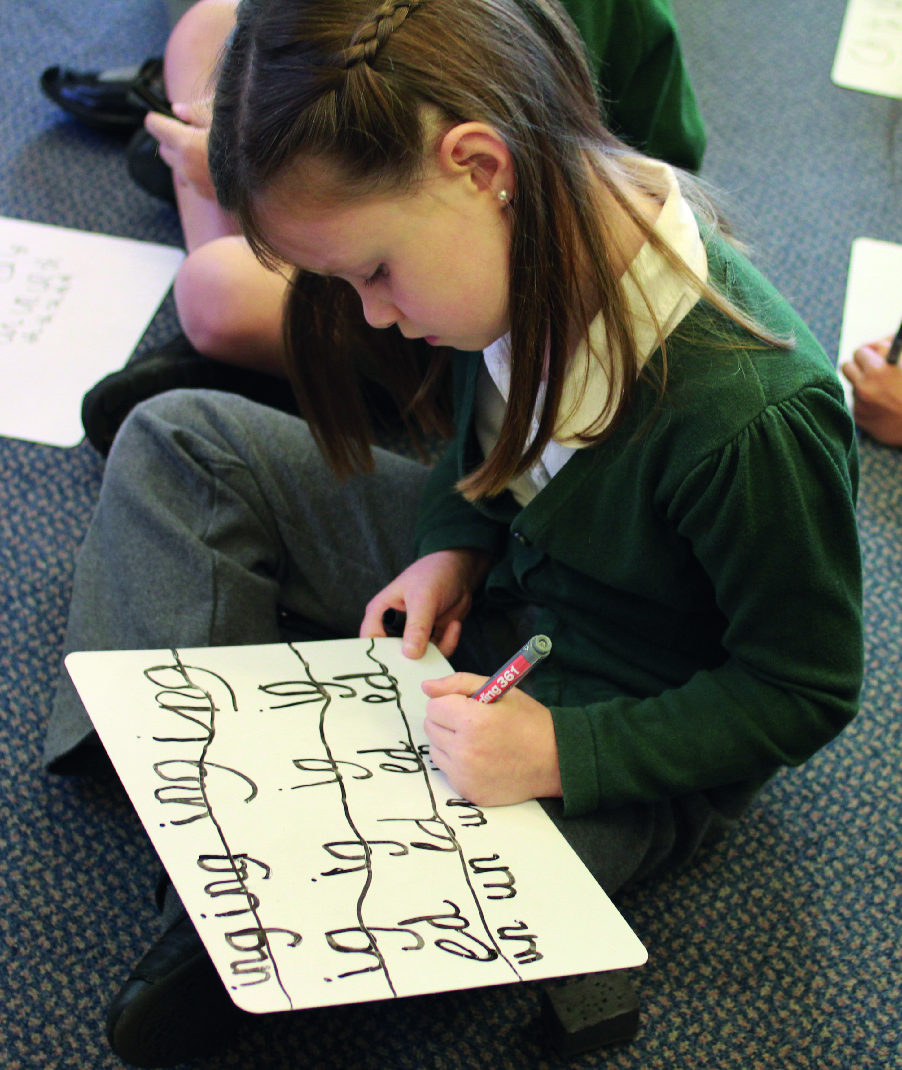 Girl writing graphemes on a whiteboard